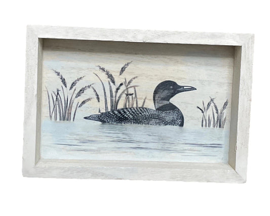 Framed artwork of a loon in a natural setting with reeds and water.