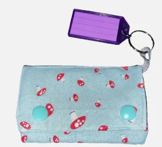 Small pouch with mushroom pattern and purple keychain on light blue background