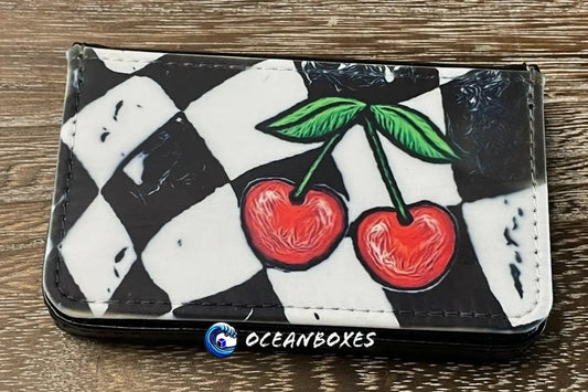 Checkered wallet with cherry design on a wooden surface, featuring the brand 'Oceanboxes'.