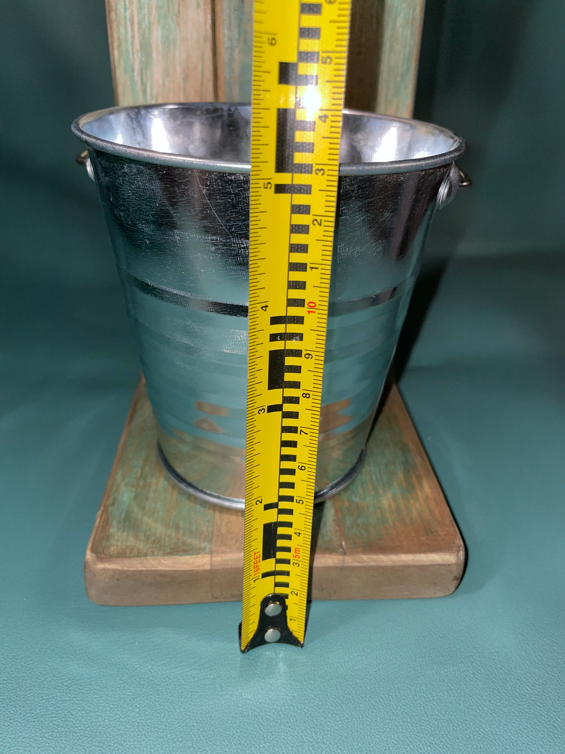Metal bucket with a yellow measuring tape against a green background