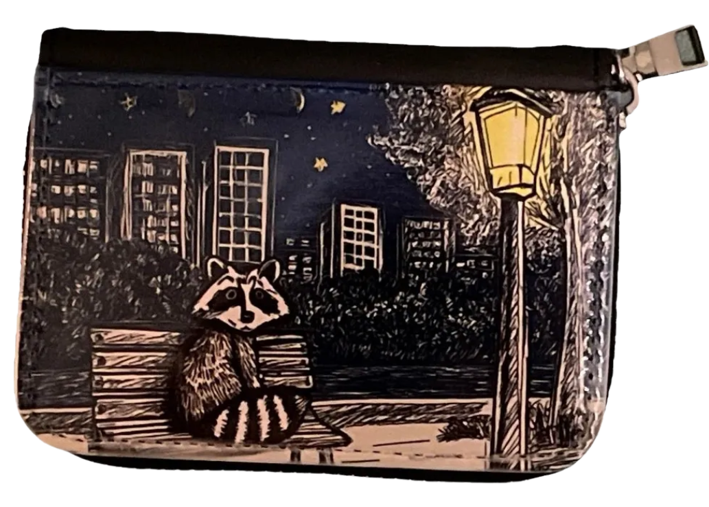 Pouch with a raccoon design on a night scene with buildings and a lamp post.