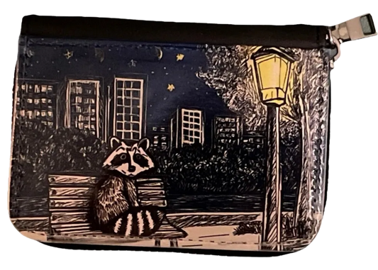 Pouch with a raccoon design on a night scene with buildings and a lamp post.