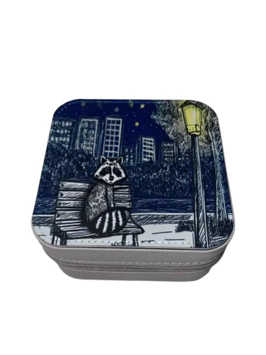 Square zippered box with a raccoon design on a bench at night, featuring a cityscape.