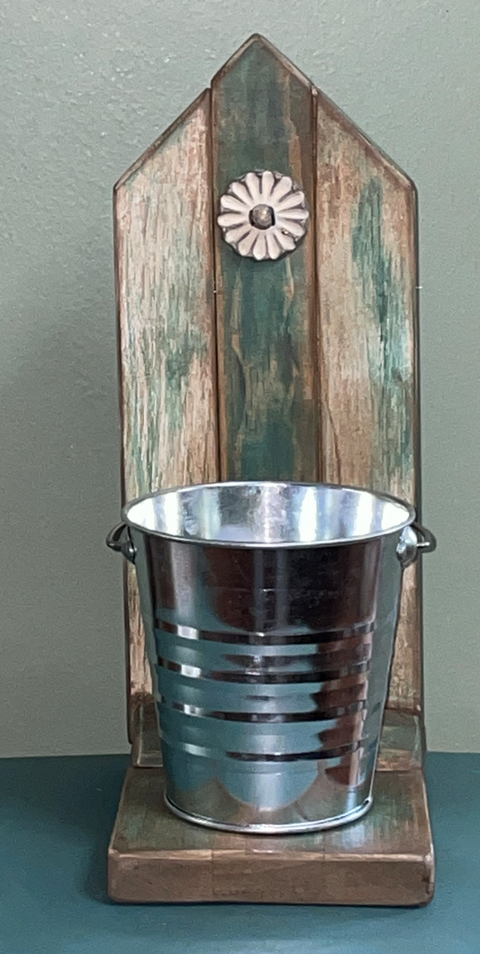 Metal bucket on a wooden stand with a decorative element against a gray background